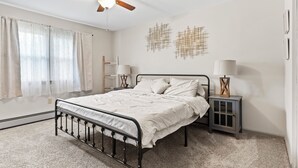 Un dormitorio con cama, ventilador de techo, dos lámparas de pared y una mesita de noche.