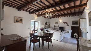 A spacious living area with a dining table, chairs, a sofa, and a television. - Villa Le Cicale in Procchio (Marciana)