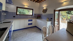 A kitchen with a window, wooden ceiling beams, and a view of the outdoors. - Villa Le Cicale in Procchio (Marciana)