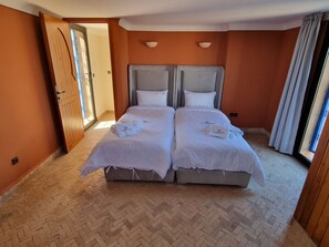 A double bed with two pillows and a blanket, a wooden door, and a herringbone-patterned floor. - Villa with a huge private pool, 15 minutes from Marrakech (Douar Erragueb / Marrakech)