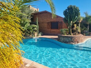 A wooden cabin with a swimming pool surrounded by tropical plants. - Villa with a huge private pool, 15 minutes from Marrakech (Douar Erragueb / Marrakech)