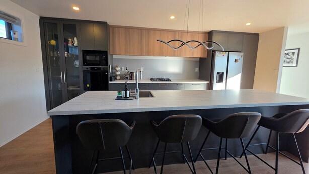 Una cucina moderna con isola centrale, sgabelli da bar e elettrodomestici integrati.
