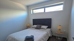 Una camera da letto con un letto, due lampade ai comodini, una finestra e un pavimento rivestito di moquette.