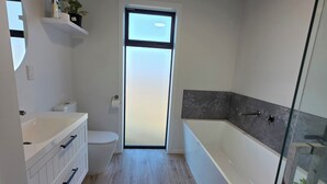 Un bagno moderno con servizi igienici, lavabo e vasca da bagno.