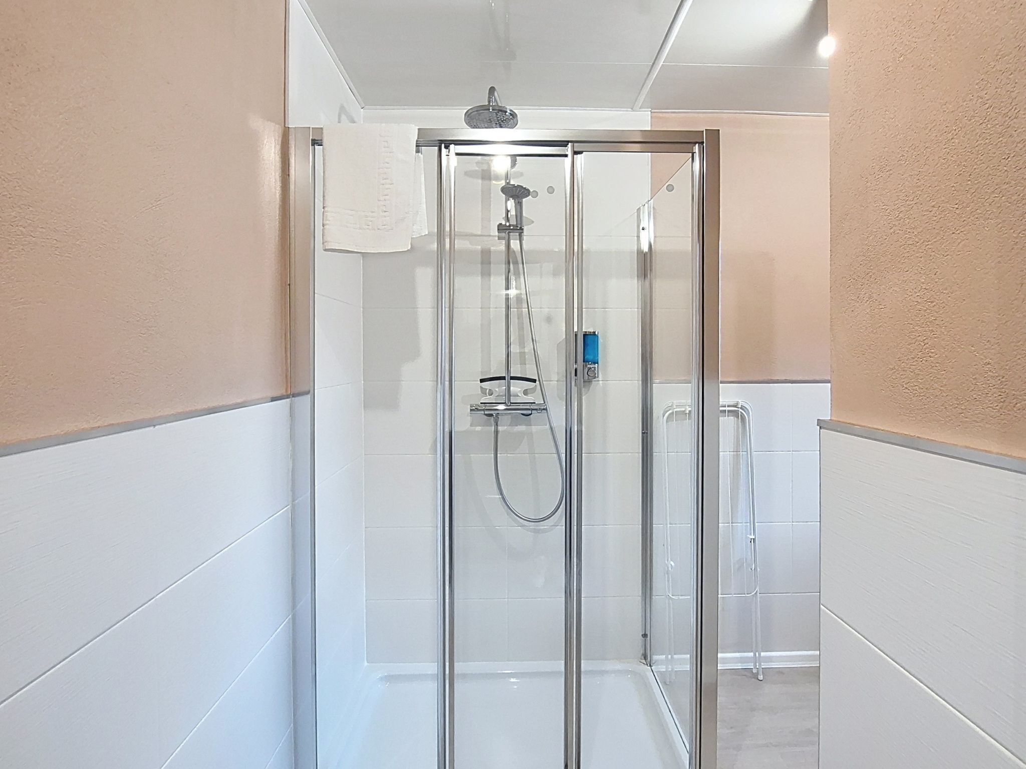 A glass-enclosed shower stall with a handheld showerhead and a wall-mounted faucet.