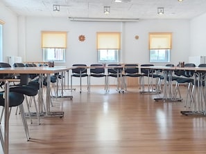 A conference room with a long table, chairs, and large windows with blinds.