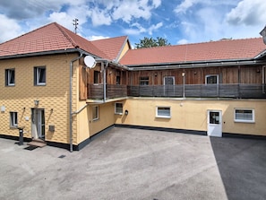 Een gebouw met twee verdiepingen, een rode pannendak, een schotelantenne en een klein balkon.