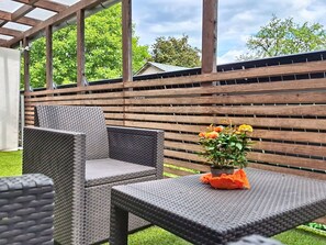 Un patio exterior con mobiliario de mimbre y una planta en maceta.