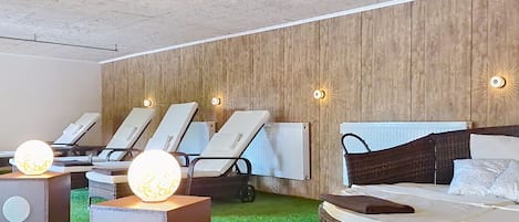 A spa room with a bed, lounge chairs, and a massage chair.