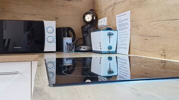 A kitchen with a microwave, coffee maker, toaster, and a clock on the wall.