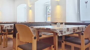 A restaurant with wooden booths and tables, a white interior, and a projector screen on the wall.