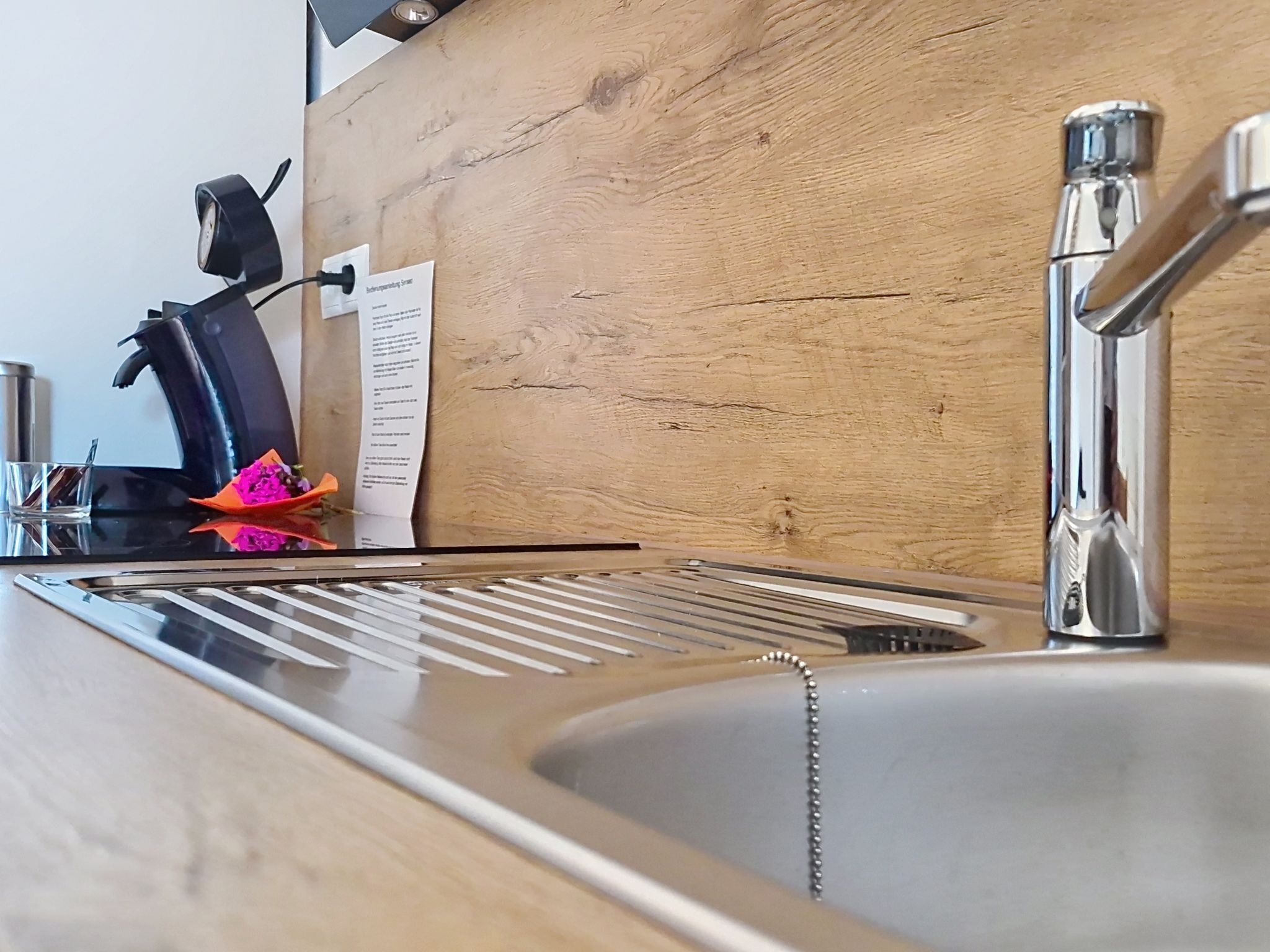 A kitchen sink with a modern faucet, a coffee machine, and a wooden countertop.