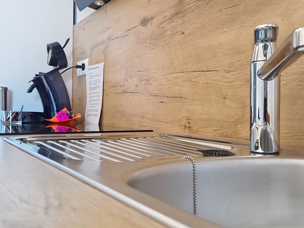 A kitchen sink with a modern faucet, a coffee machine, and a wooden countertop.