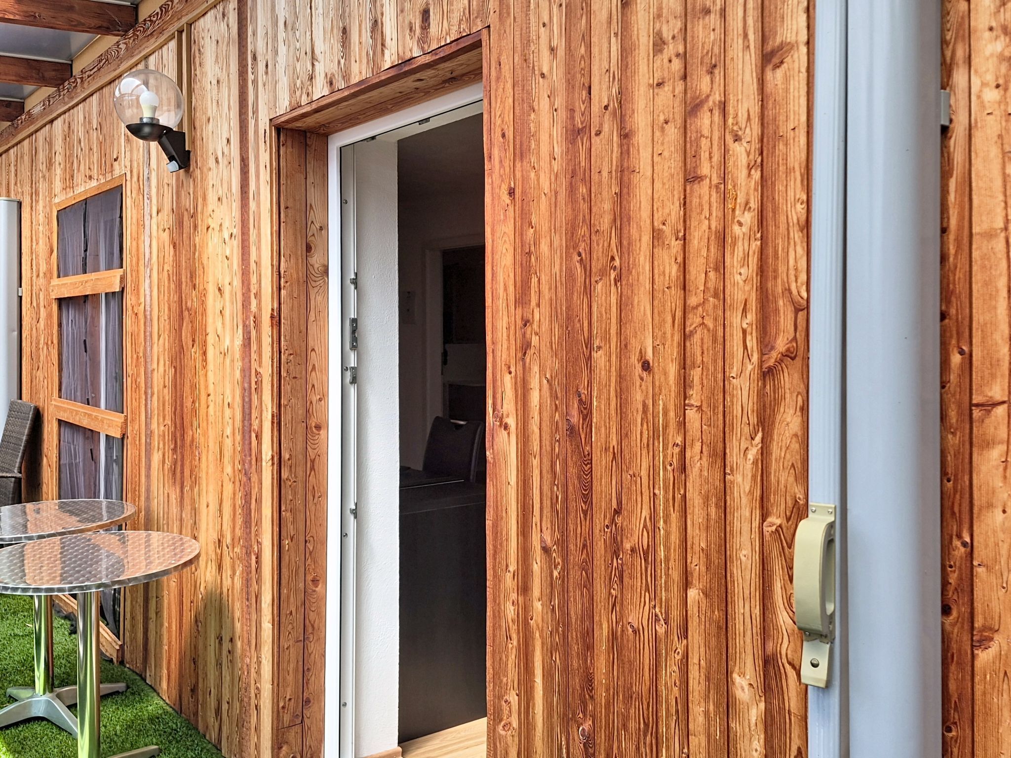 A wooden exterior with a sliding glass door leading to an interior space.