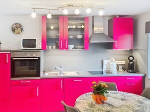 A modern kitchen with pink cabinets, a microwave, an oven, and a sink.