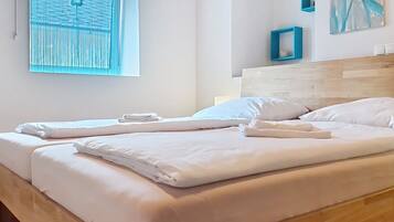 En dubbelsäng med vita sängkläder och en sänggavel i trä i ett hotellrum.