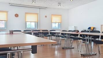 Een vergaderzaal met een lange tafel, meerdere stoelen en projectoren aan het plafond.