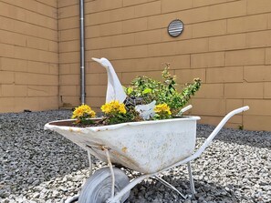 Una bressolera amb flors i una estàtua ornamental d’àngel adossada a una paret.
