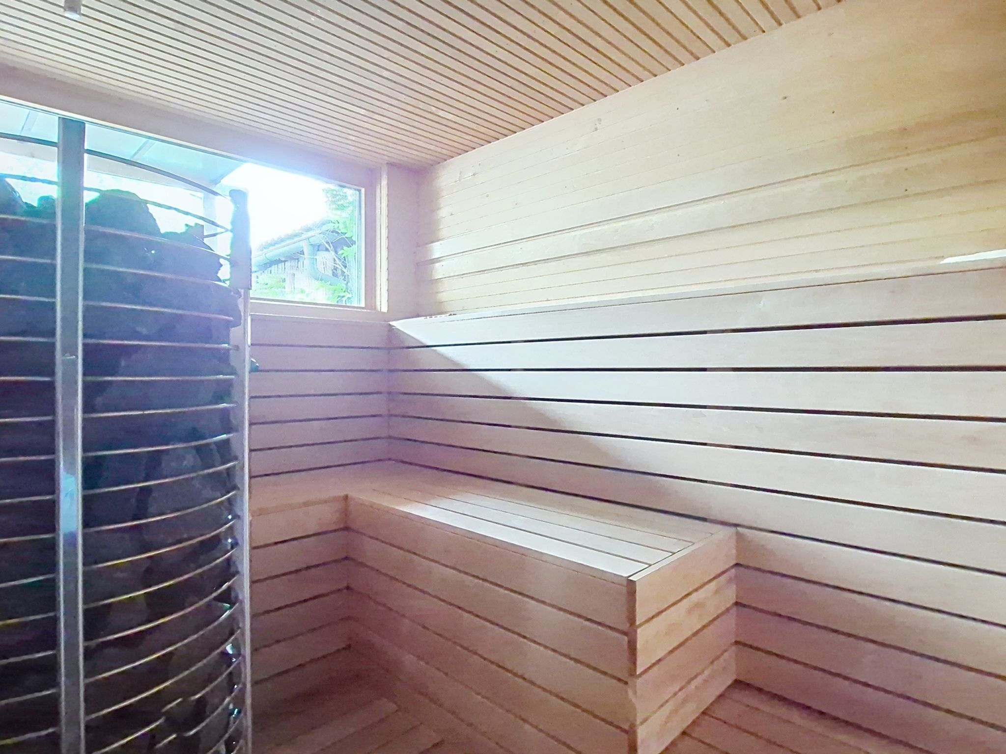 A sauna room with wooden benches and a glass door.