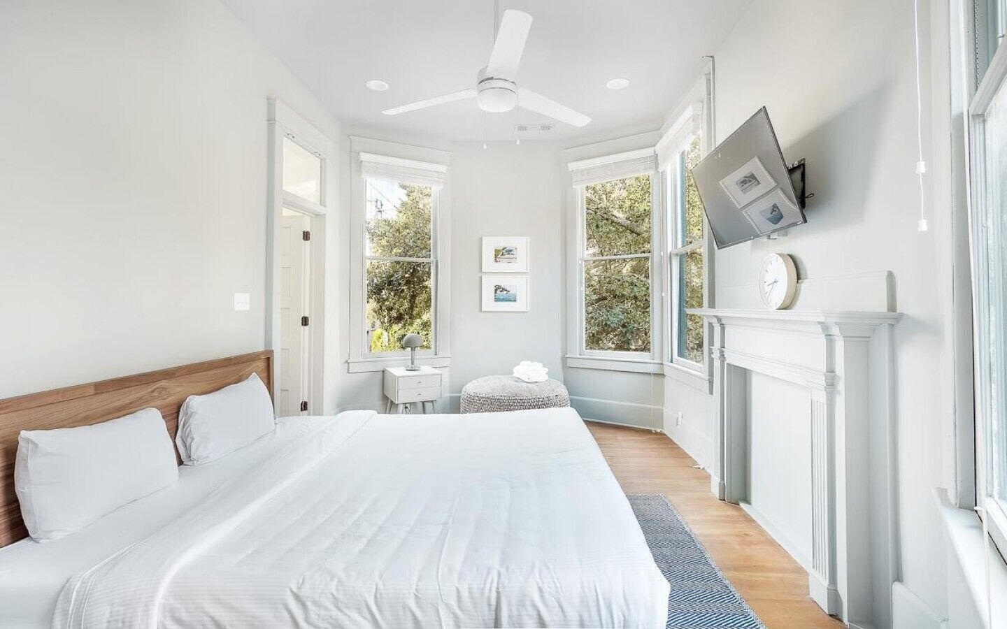 Una camera da letto con un letto grande, un ventilatore a soffitto, un camino e un televisore fissato al muro.