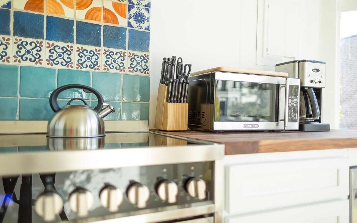 A kitchen with a microwave, kettle, and knife block.