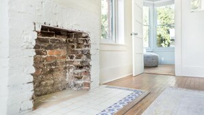 Una habitación con chimenea de ladrillo, piso de baldosas y puerta que da a un área exterior.