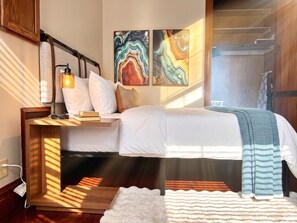 A modern bedroom with a bed, bedside tables, a lamp, and abstract wall art.