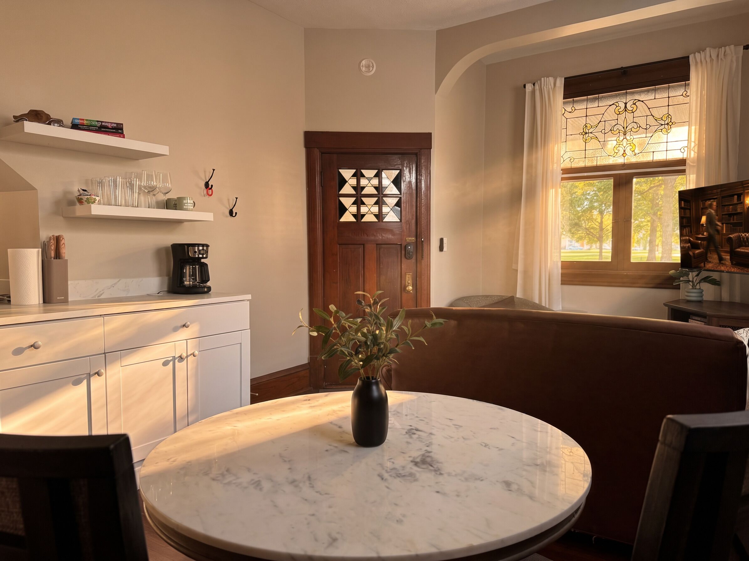 A cozy living room with a marble table, a sofa, and a coffee machine.