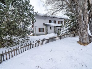 A snow-covered house with a stone foundation, wooden shutters, and a wooden fence. - Chesa Quadrellas / EG by Interhome (Samedan)