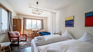 A hotel room with a bed, a chair, a table, and a window. - Chesa Quadrellas / EG by Interhome (Samedan)