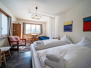 A hotel room with a bed, a chair, a table, and a window. - Chesa Quadrellas / EG by Interhome (Samedan)
