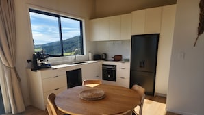 A modern kitchen with a dining area, a large window, and a view of the outdoors.
