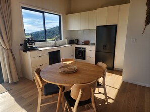 A modern kitchen with a dining area, a large window, and a view of the outdoors.