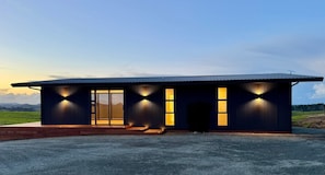 Un bâtiment moderne doté d’un toit plat, de grandes fenêtres et d’une allée gravillonnée.