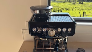 A coffee machine with two slices of toast and a cup of coffee on a table.