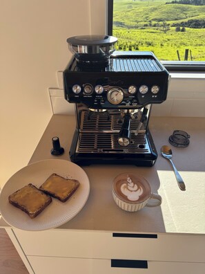 A coffee machine with two slices of toast and a cup of coffee on a table.