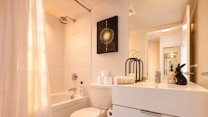 A modern bathroom with a bathtub, toilet, and a vanity with a mirror.