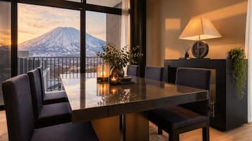 A modern dining area with a large table, chairs, and a view of a mountain.