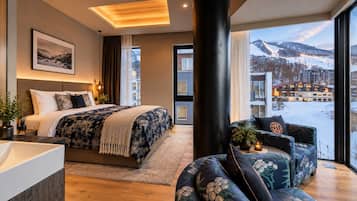 A modern hotel room with a large bed, a sitting area, and a view of a snowy landscape.