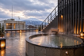 Un área de spa con un manantial termal, una escalera y vistas a una montaña nevada.