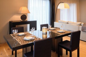 A dining area with a table set for four, including plates, cutlery, and glasses. There is a sofa in the background and a lamp on the table. - HOTELA Niseko Towers  (Kutchan)