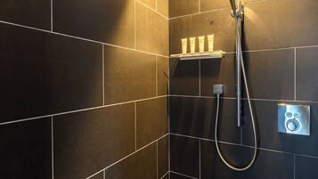 A modern shower with a handheld showerhead and a wall-mounted control panel.