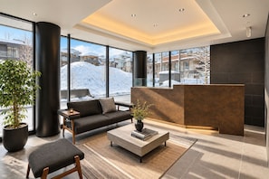 A modern lobby with a sofa, coffee table, and a reception desk. - HOTELA Niseko Towers  (Kutchan)