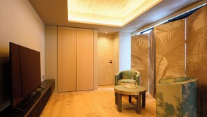 A modern living room with a flat-screen TV, a round coffee table, and a chair. - HOTELA Niseko Towers  (Kutchan)