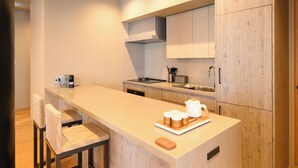 A modern kitchen with a central island, bar stools, a built-in oven, and a microwave. - HOTELA Niseko Towers  (Kutchan)