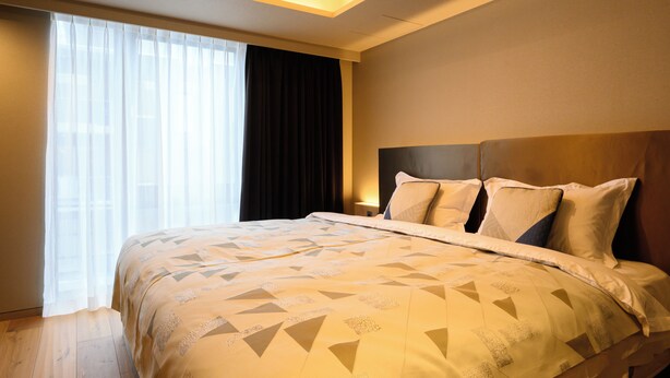 A hotel room with a large bed, a window with curtains, and a ceiling light. - HOTELA Niseko Towers  (Kutchan)