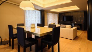 A modern living room with a dining area, wooden flooring, and a flat-screen TV. - HOTELA Niseko Towers  (Kutchan)