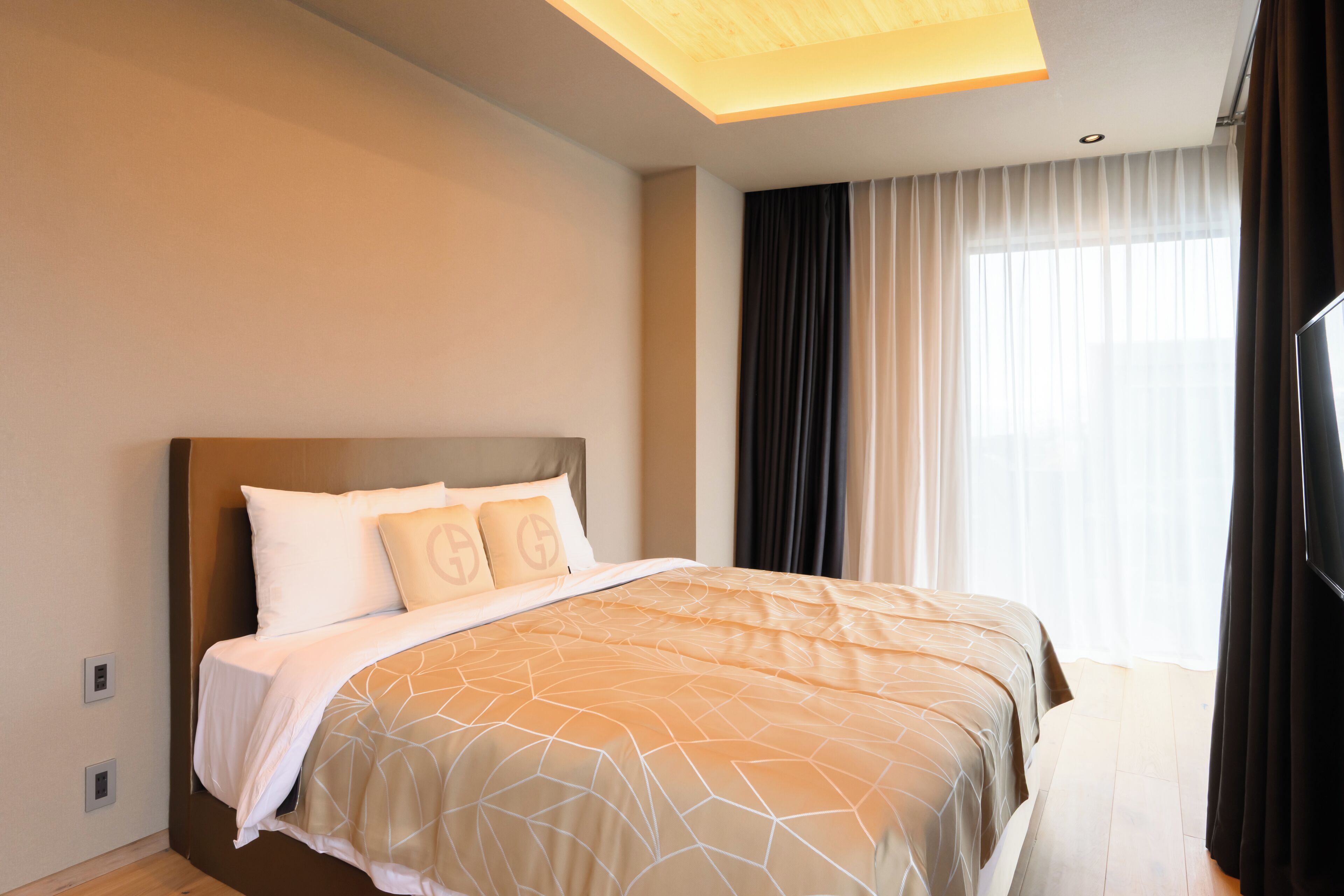 A hotel room with a bed, a television, and a window with curtains.