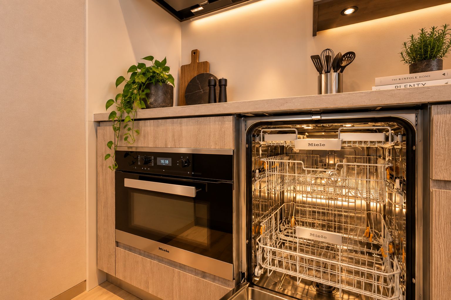 A kitchen with a built-in dishwasher, oven, and a potted plant on the countertop.