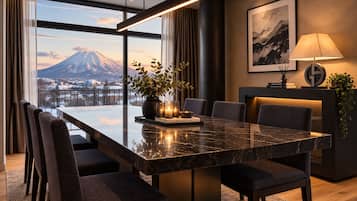 A modern dining area with a large table, chairs, and a view of a mountain.